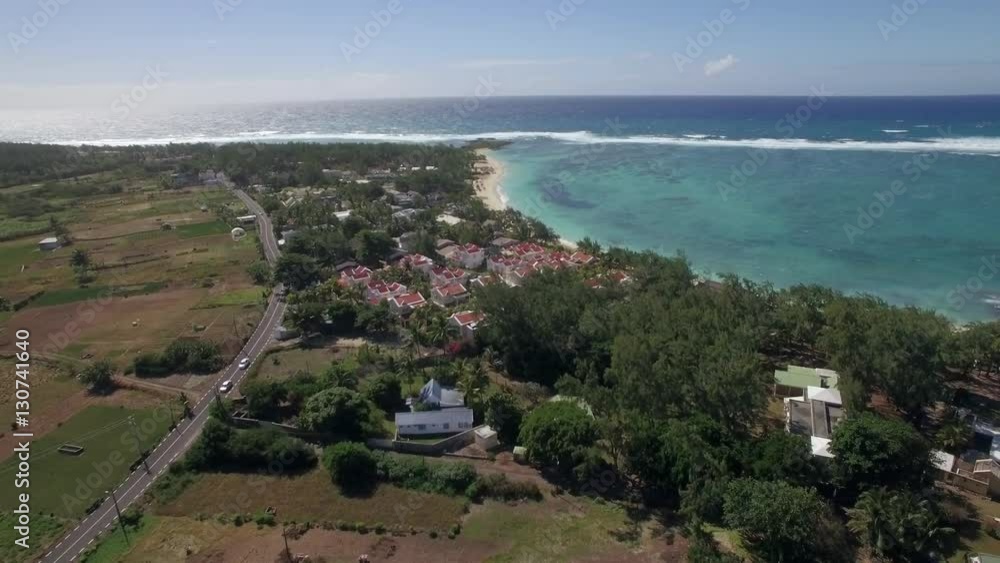 Aerial shot of Mauritius. Houses on the coastal line of island and green farmlands behind. Scenic view with Indian Ocean seascape and skyline Aerial shot of Mauritius. Houses on the coastal line of island and green farmlands behind. Scenic view with Indian Ocean seascape and skyline