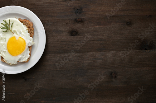 fried egg with rosemary on a white plate