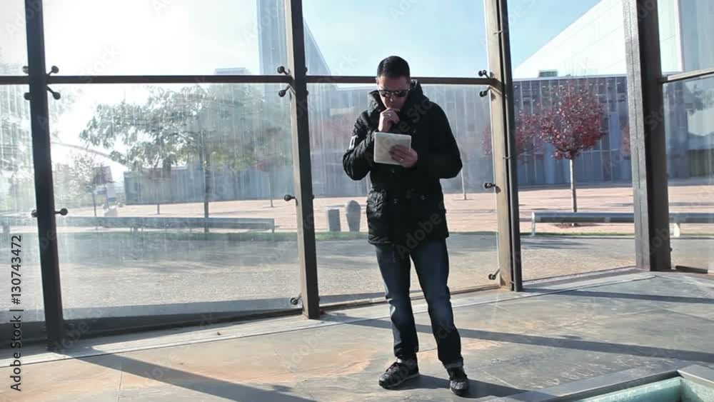 Hombre caminando en la calle con la tablet. Estilo de vida y vida moderna, paisaje urbano. Concepto de tecnología y comunicación. Rayo de sol y puesta de sol
