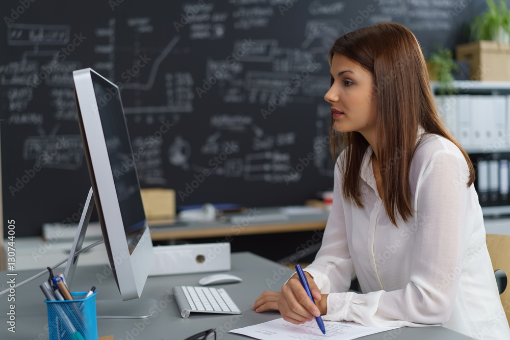 frau im büro schaut konzentriert auf ihren computer-bildschirm frau im büro schaut konzentriert auf ihren computer-bildschirm
