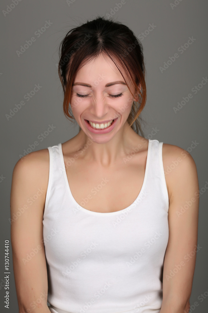 Smiling girl in sleeveless shirt. Close up. Gray background Smiling girl in sleeveless shirt. Close up. Gray background