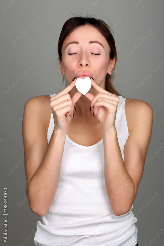 Girl kissing small heart. Close up. Gray background Girl kissing small heart. Close up. Gray background