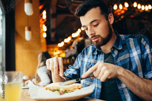 Vászonkép Handsome young man having lunch in elegant restaurant alone