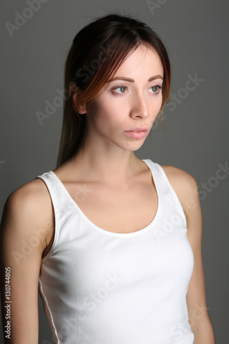 Girl with red hair in tanktop. Close up. Gray background