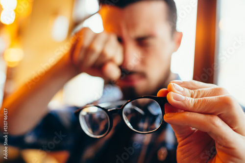 Closeup portrait of young man with glasses, who has eyesight problems photo