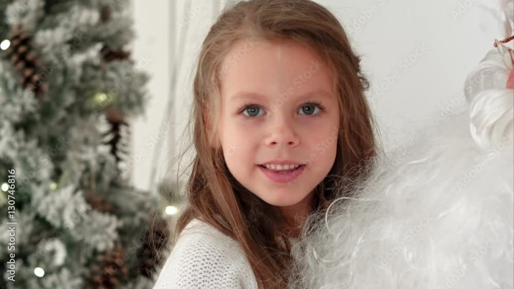 Sweet little girl sitting on Santa Claus lap describing what presents she wants for Christmas Sweet little girl sitting on Santa Claus lap describing what presents she wants for Christmas