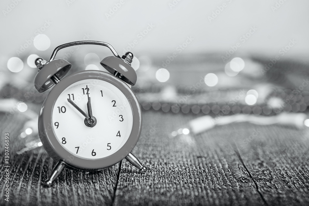red alarm clock on a textured wooden board with lights and beads red alarm clock on a textured wooden board with lights and beads