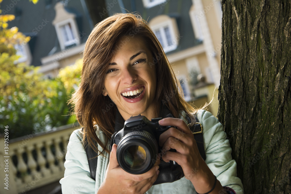 Beautiful woman at the park with a camera. Smiling and taking photos.
