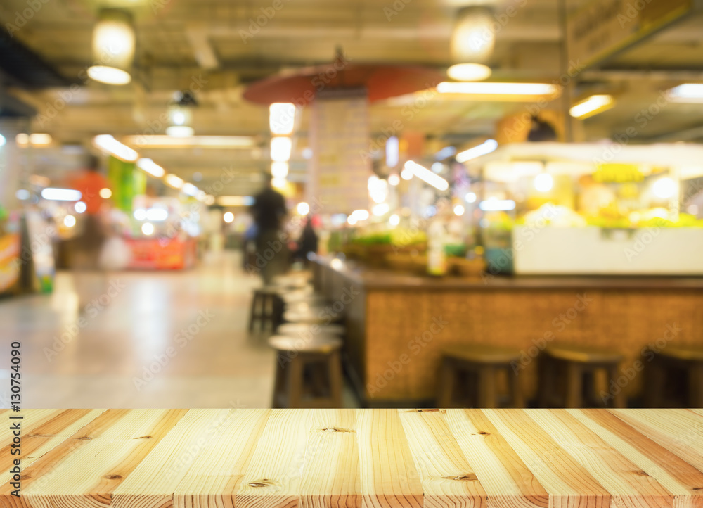 Defocused or blurred photo of food court montage with wood table top use for background.