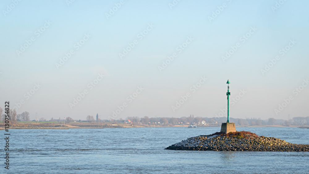 Green beacon in the river Waal in the evening sun