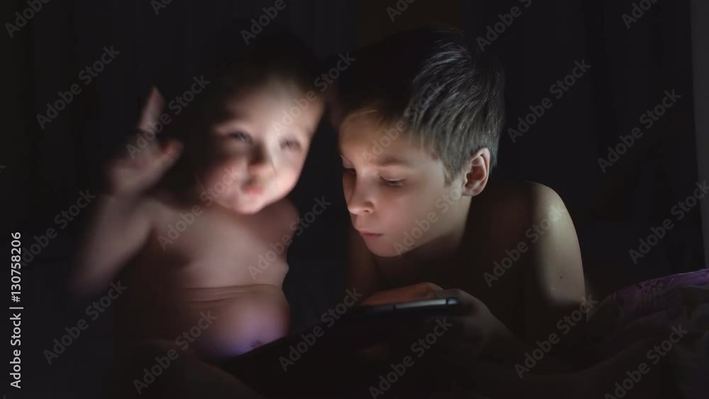 Two young brothers playing with tablet at night. 4K Two young brothers playing with tablet at night. 4K