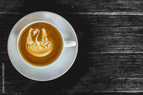 Close up white cup of Coffee, latte with beautiful latte art on the black wood background.
