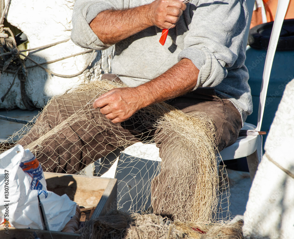 fisherman repairing a fishnet in his boat