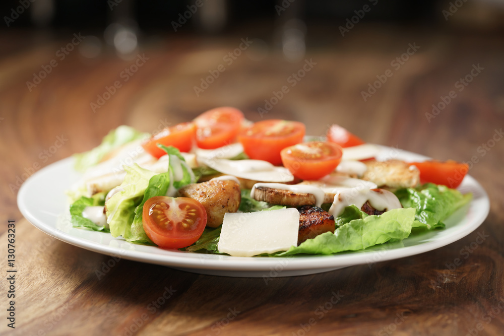caesar salad with cherry tomatoes on wooden table caesar salad with cherry tomatoes on wooden table