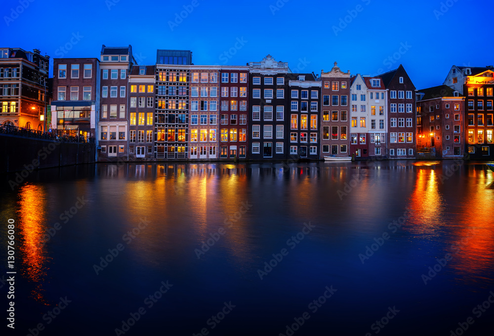 Houses facades over canal with reflections illuminated at night, Amsterdam, Netherlands, retro toned