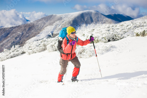 Girl with backpack walking on snow in the mountains.