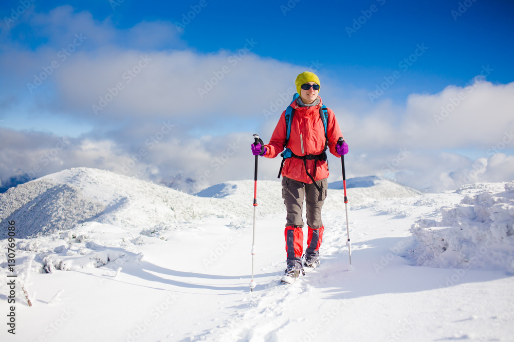 Girl with backpack walking on snow in the mountains.