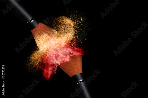Makeup brushes applying powder isolated on black