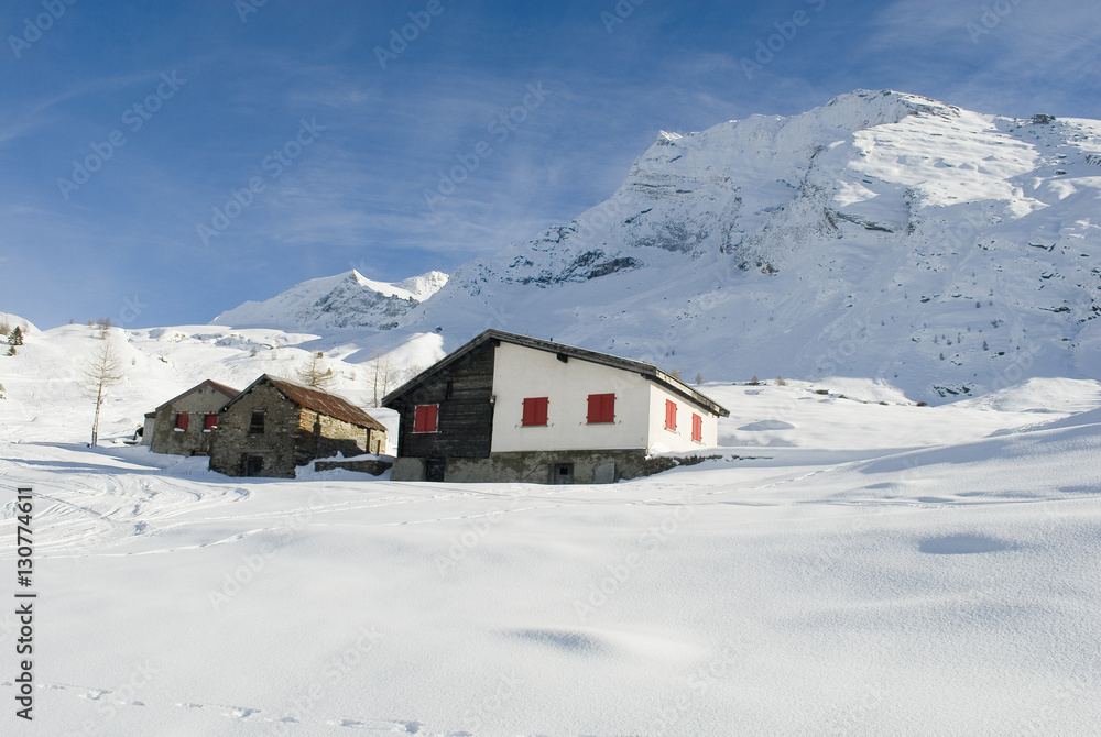 Piccola baita di montagna in legno e pietra nella neve fresca del passo del sempione, alpi svizzera