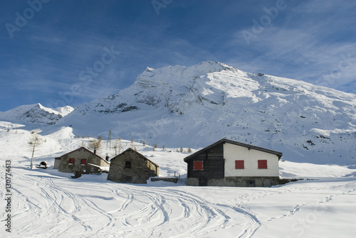 Piccola baita/chalet di montagna in legno e pietra nella neve fresca del passo del sempione, alpi svizzera