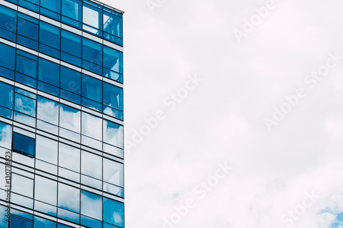 Office building with blue mirrored windows and reflection of clo