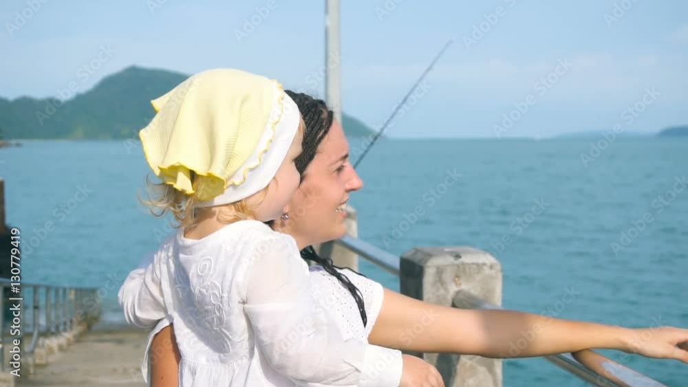 Mother with little daughter looking afar in the ocean Mother with little daughter looking afar in the ocean