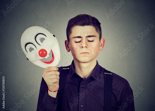 Sad man taking off happy clown mask. Split personality photo