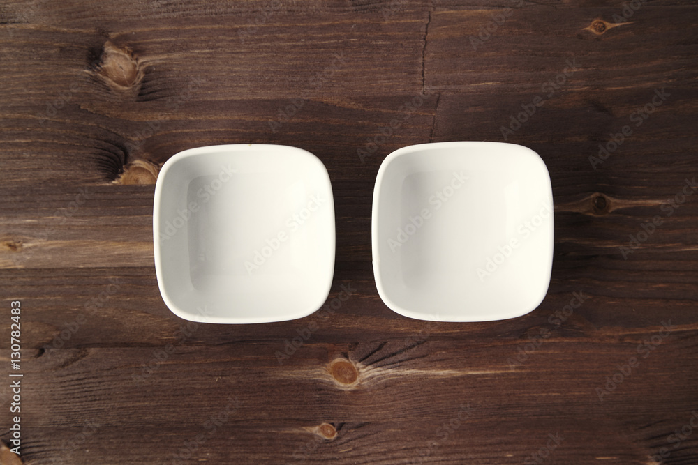 Two ceramic white small bowls at the rustic wooden table Two ceramic white small bowls at the rustic wooden table