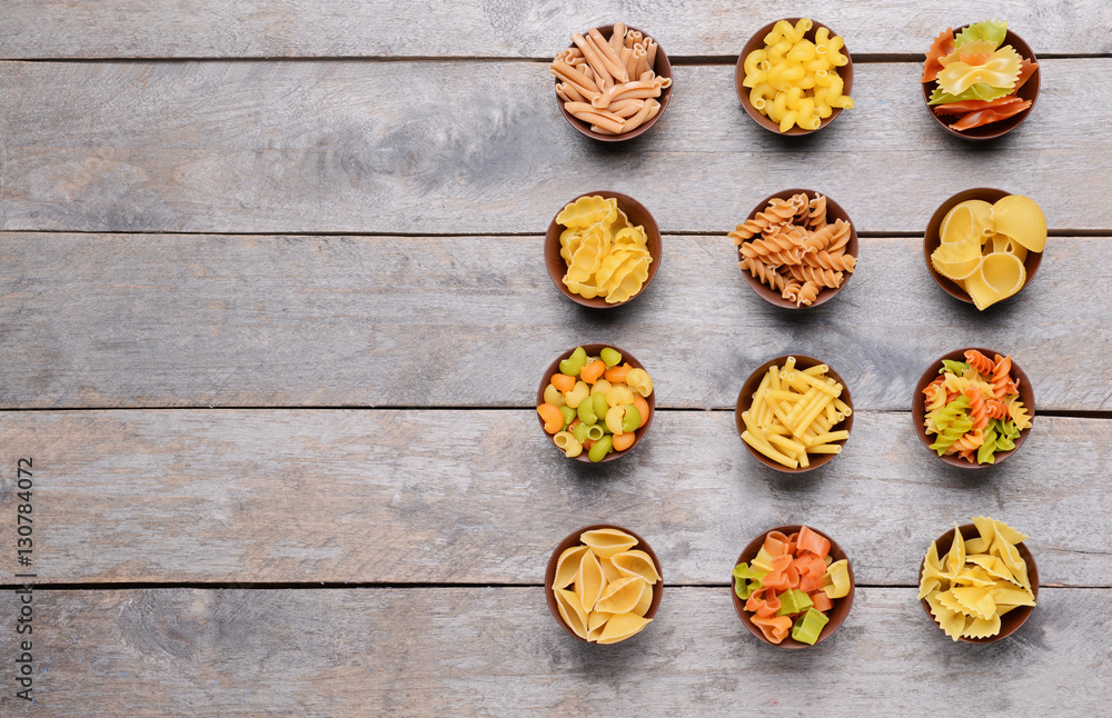 Different kinds of pasta in bowls on wooden background Different kinds of pasta in bowls on wooden background