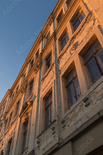 Old dirty building facade with crumbling paint and plaster, broken windows, at beatiful dusk in Goerlitz, Saxony.