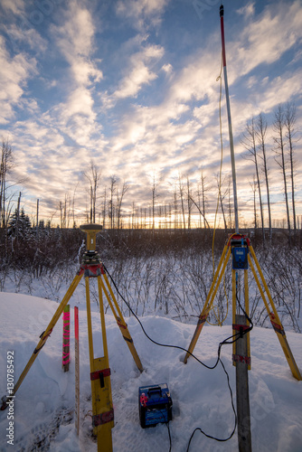 Survey equipment set up in snow at sunset