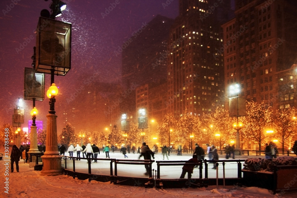 Winter night in Chicago. People enjoying ice skating at Millennium park ice rink during snowy night in Chicago.
