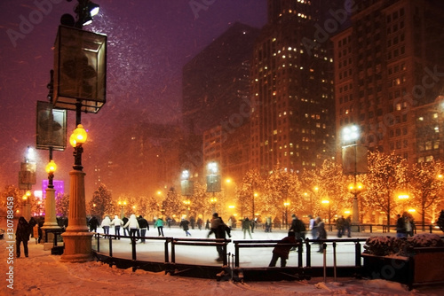 Winter night in Chicago. People enjoying ice skating at Millennium park ice rink during snowy night in Chicago.