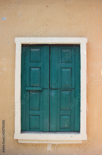 Ancient green wood window on orange tone wall © evepj