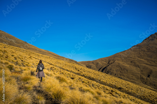 Foto Woman hiker walking on the golden tussock meadow