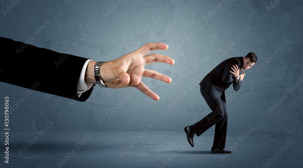 Business man running away from a huge hand concept Business man running away from a huge hand concept