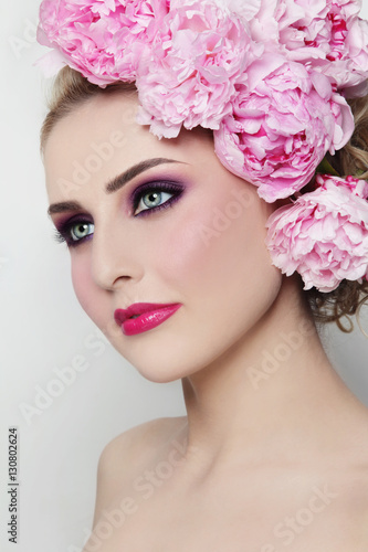 Young beautiful woman with stylish make-up and peonies in her hair