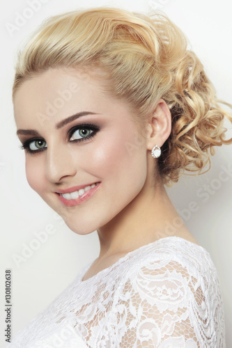 Portrait of young beautiful blonde happy smiling bride in lacy dress