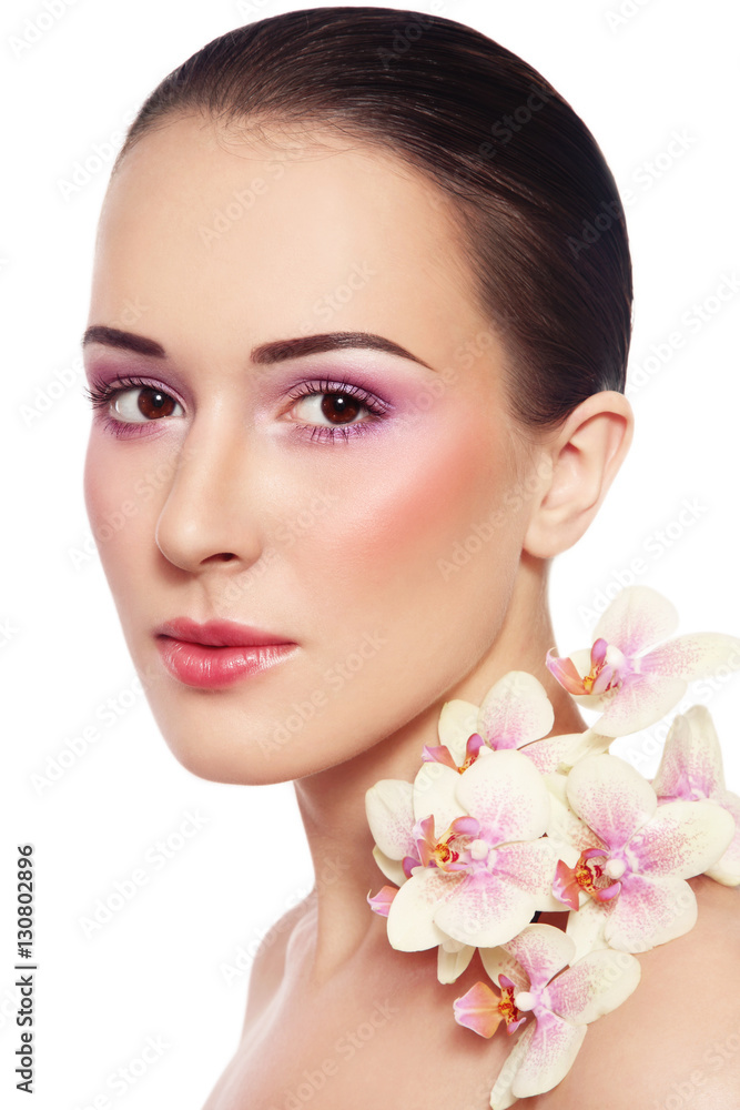 Portrait of young beautiful woman with glowing make-up and orchid over white background