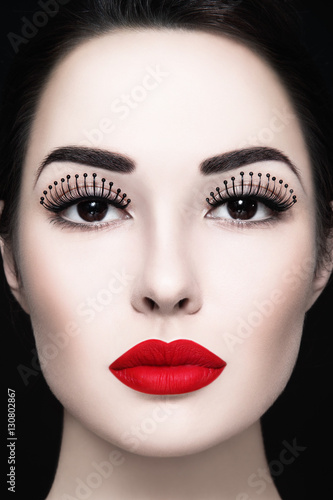 Close-up portrait of young beautiful woman with fancy false eyelashes and matte red lipstick
