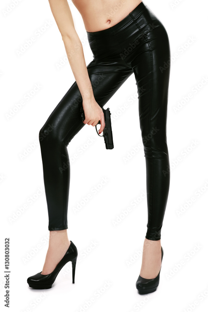 Long legs of slim sexy girl in leather skinny pants and high heels holding  a pistol in her hand over white background Stock Photo | Adobe Stock