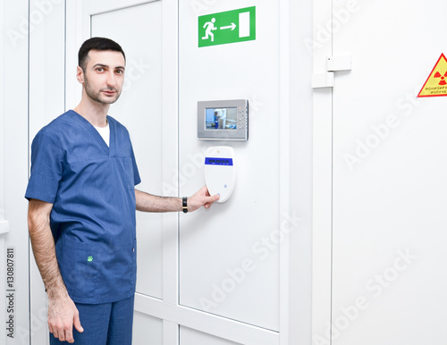 The doctor stands near the X-ray machine control panel to capture teeth