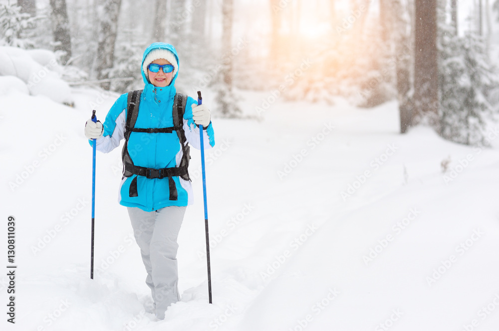 Woman Smiling in winter forest holding ski poles.