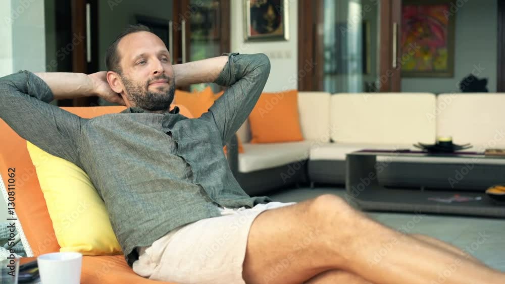 Young, happy man relaxing on lounger on patio
Young, happy man relaxing on lounger on patio
