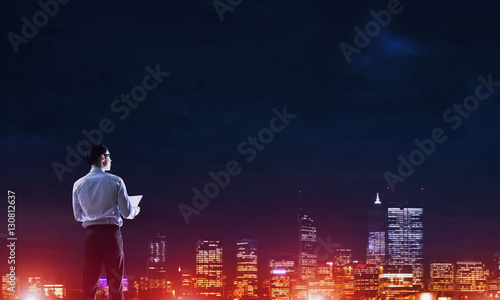 Fototapeta Naklejka Na Ścianę i Meble -  Businessman viewing night glowing city
