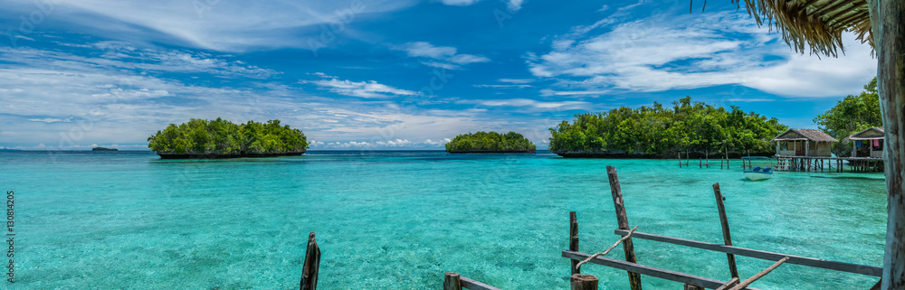 Beautiful Blue Lagoone with some Bamboo Huts, Kordiris Homestay, Palmtree in Front, Gam Island, West Papuan, Raja Ampat, Indonesia Beautiful Blue Lagoone with some Bamboo Huts, Kordiris Homestay, Palmtree in Front, Gam Island, West Papuan, Raja Ampat, Indonesia