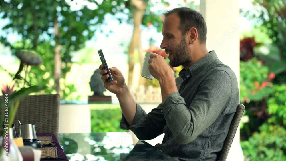 Young, happy man using smartphone and drinking beverage in garden
Young, happy man using smartphone and drinking beverage in garden