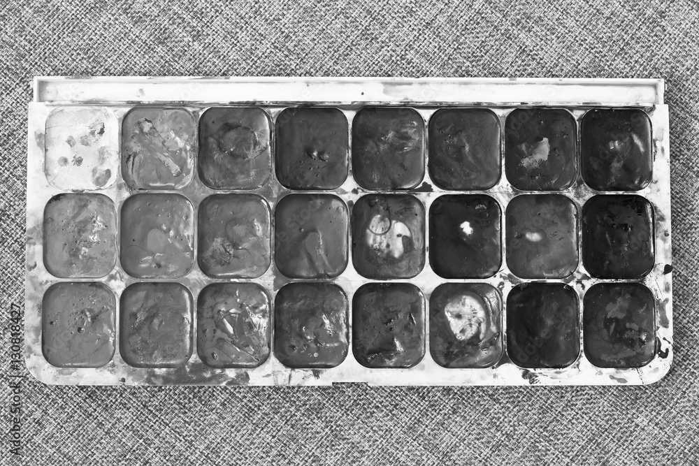 Watercolor paints box on fabric background. Used paint palette. Black