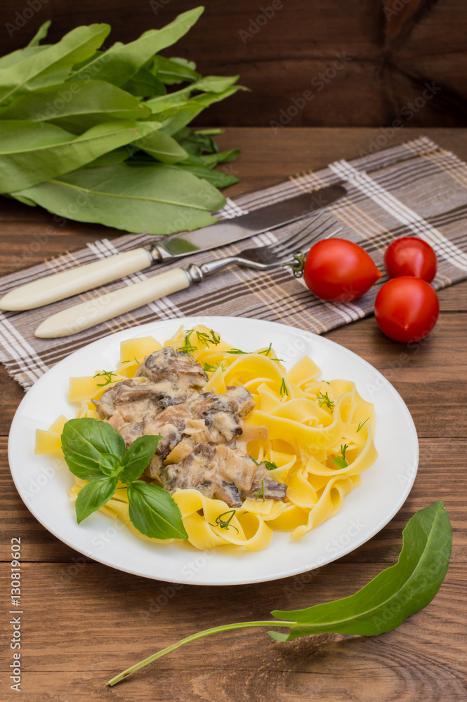 Fettuccine pasta in a creamy sauce with mushrooms on plate wooden table. top view. Close-up