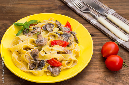 Fettuccine pasta in a creamy sauce with mushrooms on  plate   wooden table. Horizontal top view. Close-up photo